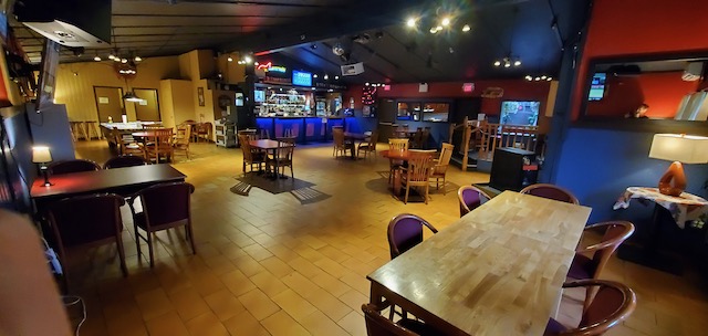 Inside the public house: wooden tables, the long bar and big screens under warm lights